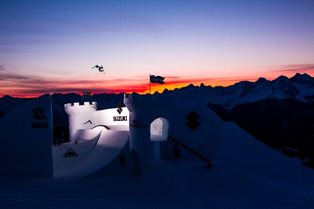 Snowboarderin springt bei Sonnenaufgang über eine Schneeburg